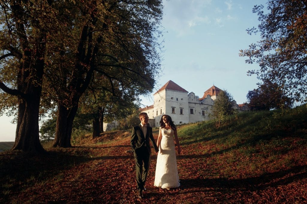 stylish luxury bride and groom posing together near old castle at sunset